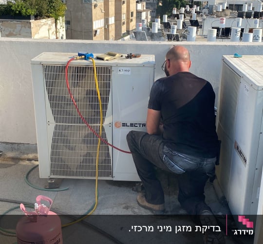 טכנאי עובד על מזגן עם בלון גז ורד